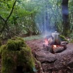 Ein Teekessel dampft auf einem kleinen Feuer im Märchenwald - Romantik pur bei Wildnistouren